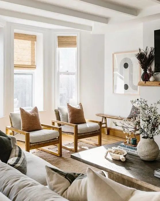 a sophisticated neutral living room with a large sofa, white chairs with warm-stained wood, a reclaimed wood coffee table for a contrast