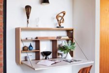 a stylish Murphy desk with a stained plywood base and a white desktop plus some display shelves inside and some artworks on top