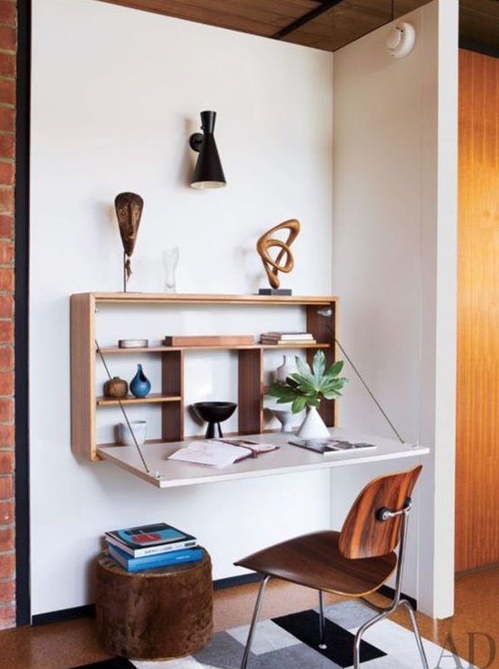 a stylish Murphy desk with a stained plywood base and a white desktop plus some display shelves inside and some artworks on top
