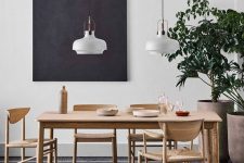a stylish Scandinavian dining room with a blonde wood dining set, a tiled floor, pendant lamps and a black artwork