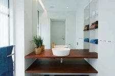 a stylish modern bathroom done in white but with a statement colorful tile floor and matching blue textiles