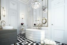 a super chic and elegant monochromatic bathroom with a patterned floor, a statement chandelier, a large mirror, a sculptural tub and gilded touches
