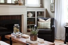 a taupe living room with a fireplace, a white sofa, a black and white chair, a low coffee table and a mirror