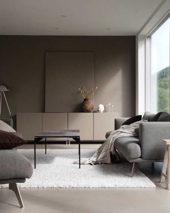 a taupe living room with a grey sofa, a taupe sideboard and an artwork, a coffee table and a textural rug