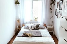a tiny boho bedroom with a stained bed, neutral bedding, a mini step with a lamp and a round side table as a nightstand