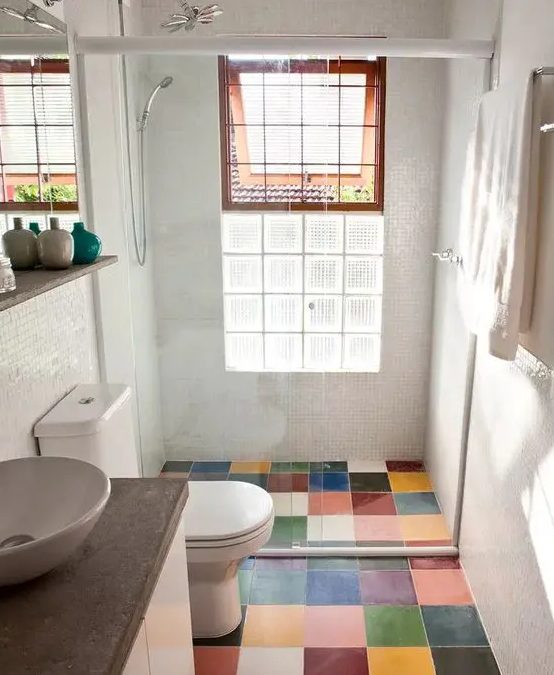 a tiny modern bathroom with a multi color tile floor, white appliances and a vanity with a stone countertop, a window for natural light