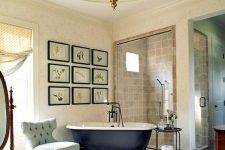a traditional French bathroom with neutral walls, tan tiles and a beautiful blue ceiling, a black clawfoot tub, a shower space and a gallery wall