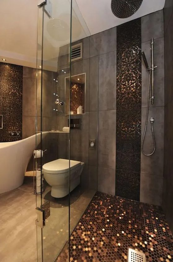 a unique bathroom clad with aged metal tiles, with a shower space with a penny tile floor and glass doors, a chic bathtub and penny tile accents