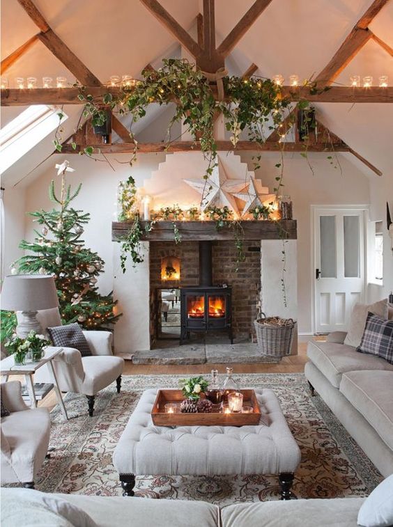 a vintage neutral living room with a reclaimed wooden mantel, grey vintage furniture, potted greenery, lights and a Christmas tree