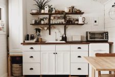 a white Scandi kitchen with sleek cabinets, a blonde wood table and matching chairs, dark-stained butcherblock countertops
