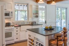 a white farmhouse kitchen with shaker style cabinets, black countertops, a rounded kitchen island with wine storage