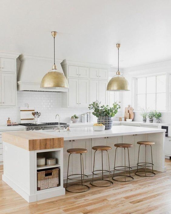 a white farmhouse kitchen with shaker style cabinets, white stone countertops, a white subway tile backsplash and a storage kitchen island with open storage niches