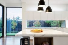 a white minimalist kitchen with sleek cabinetry, a large kitchen island with a white marble countertop and open storage niches