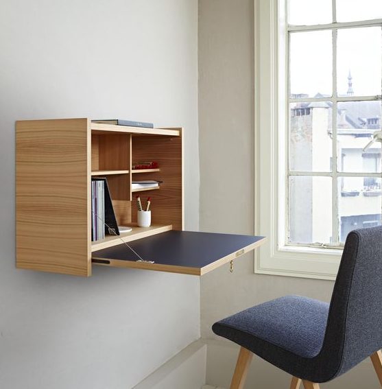 an elegant minimalist Murphy desk done in light colored plywood and navy, with stylish and neat storage compartments inside