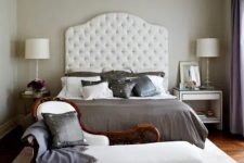 an elegant vintage-inspired bedroom with a creamy bed with an extended headboard, a chic daybed, a vintage side table and a modern white nightstand