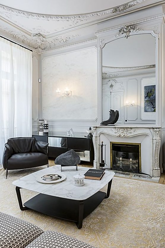 sophisticated molding on the walls, ceiling and fireplace make the contemporary black and white furniture more balanced