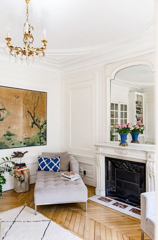 white walls with molding and warm colored hardwood parquet floors create a chic combo for a Parisian living room