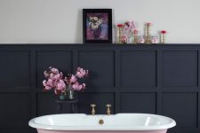 02 a beautiful bathroom with printed tiles on the floor, black paneling on the walls, a pink clawfoot bathtub, blooms and lovely artwork is amazing