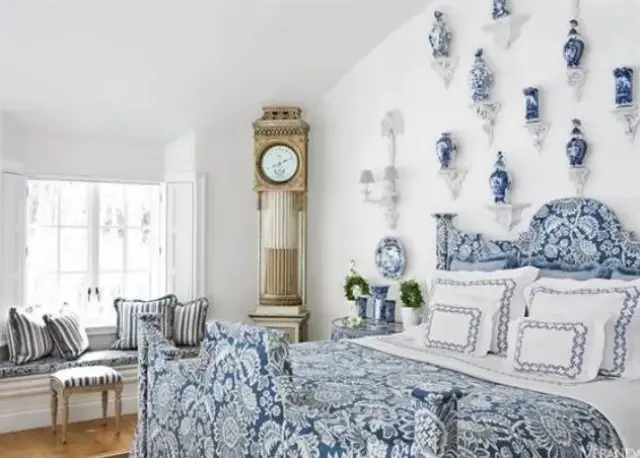a chic blue bedroom with porcelain vases on display and a chic vintage clock in the corner that matches the vintage style
