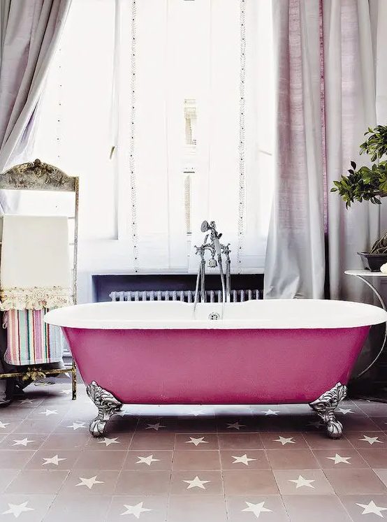 a beautiful bathroom with a blush star print tile floor, a bright pink bathtub, lilac curtains, a stand for towels and potted greenery