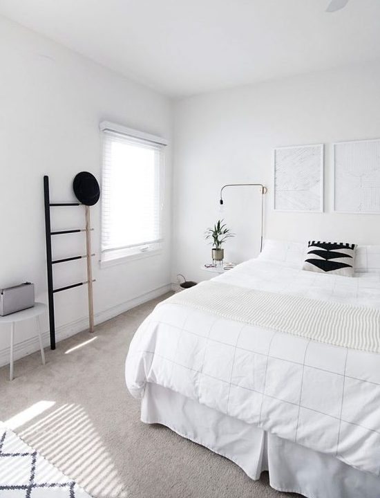 a clean Nordic bedroom with a white bed, artworks, a ladder, lamps and a stool - blakc for drama