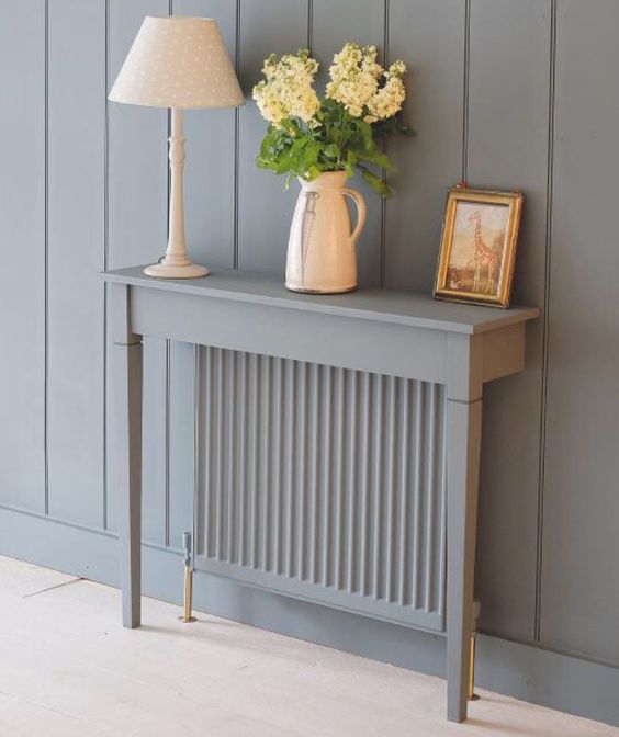 a grey radiator with a matching grey half console table with blooms, art and a white lamp is a lovely idea for a modern space