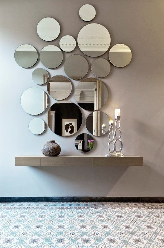 an arrangement of round mirrors of various sizes and a floating vanity for an ethereal look
