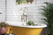 06 a black and white tile floor, white subway tiles on the walls, a mustard clawfoot bathtub and potted plants plus a bold print