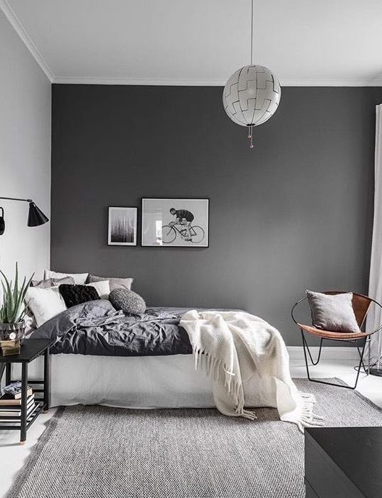 a contemporary Scandinavian bedroom with a dark wall, monochromatic bedding, lamps and lights and a grey rug