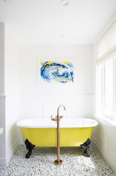 a catchy bathroom with a black and white printed floor, a yellow clawfoot tub, a bold artwork and a statement fixture is wow