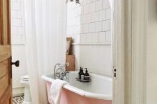 08 a chic bathroom with black and white tiles on the floor, white square tiles on the walls, a pink clawfoot bathtub, some greenery and white curtains