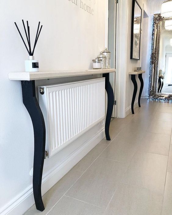a modern radiator with a black and white half table as a console, and a matching half table attached to the wall nexh to the door