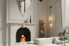 08 a refined neutral space with a fireplace, elegant neutral furniture, a catchy black chandelier and a uniquely shaped mirror over the fireplace