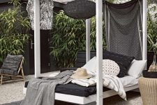 09 a cabana-style wooden daybed with a hanging black lamp, a curtain and lot sof pillows and blankets welcomes with its look