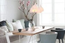 09 a dreamy Nordic dining space with a built-in bench and muted pillows, a wooden table, muted color chairs and a cluster of pendant lamps