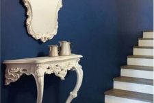 09 a navy wall and a contrasting vintage carved half console table, a matching mirror for adding a refined vintage feel to the space