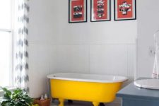 10 a crispy white bathroom with a bold yellow clawfoot bathtub, a blue vanity, a colorful gallery wall and a potted plant