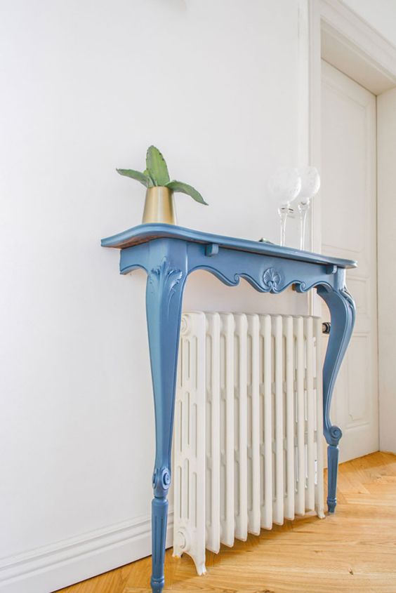 a radiator covered with a refined vintage blue console half table, with some decor will add elegance to your space