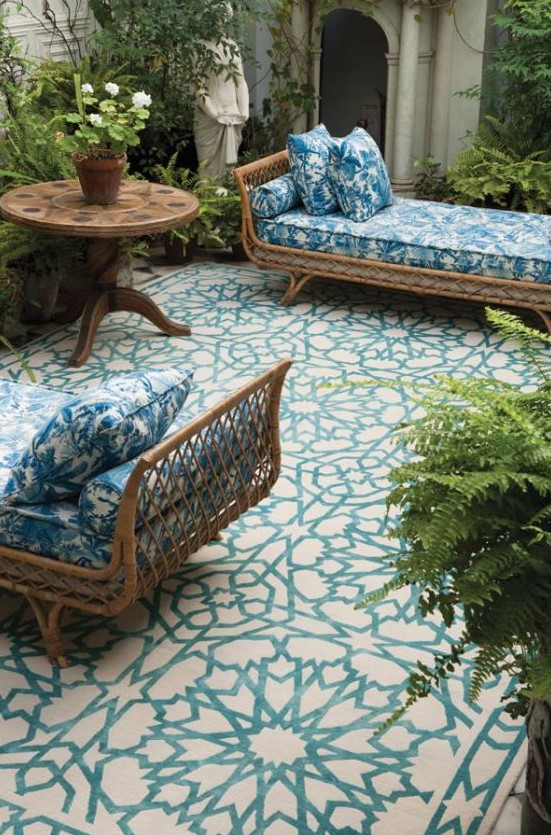 a couple of elegant rattan daybeds dressed up with blue and white printed bedding that matches the mosaic floor