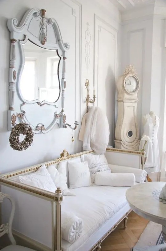 a luxurious interior in white, pastels and gold, with an antique mirror and a vintage clock in the corner is a lovely and refined space to be