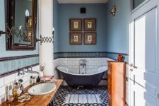 12 a gorgeous vintage bathroom done in blue, with a black and white tile floor, a navy clawfoot bathtub, stained furniture, artwork and a mirror