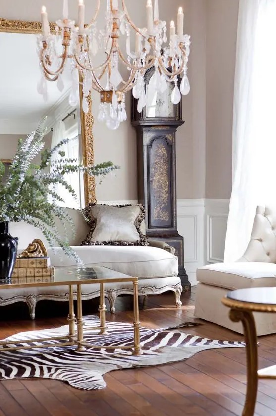 a luxurious interior with a dark-stained grandfather's clock, a refined sofa and an animal print-inspired rug, a glass table and a beautiful and chic chandelier