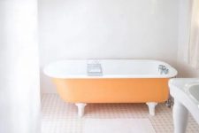 13 a light-filled bathroom with light blue walls, an orange clawfoot bathtub, a crystal chandelier and a vintage gallery wall