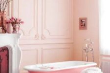 15 a lovely girlish bathroom with blush paneled walls, a vintage fireplace, a pink clawfoot bathtub, a shabby chic chair and some blooms