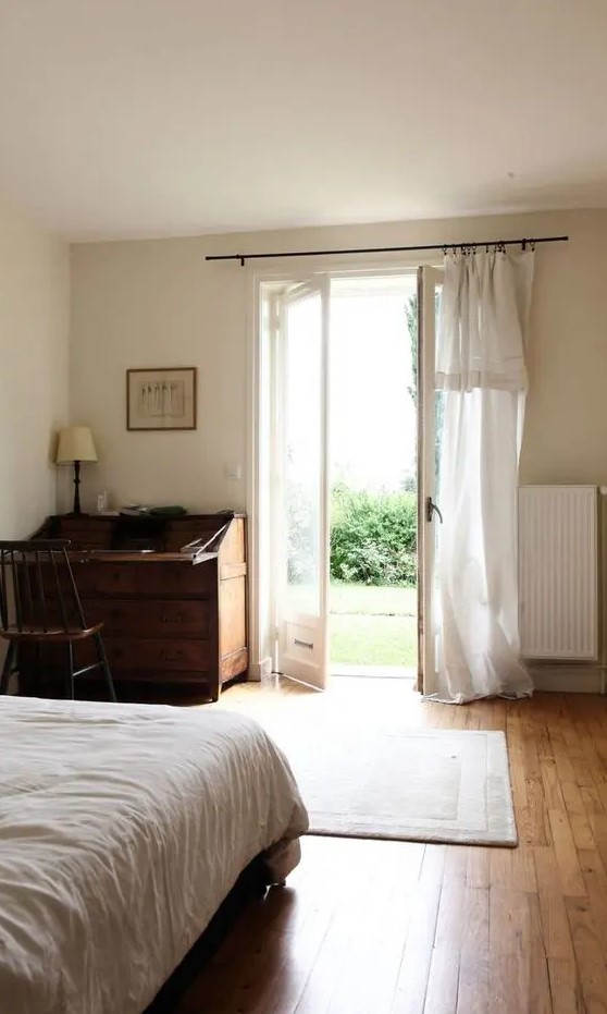 a vintage-inspired bedroom with much negative space for a relaxed feeling and doors to the garden