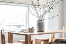 17 a Nordic dining room with a wooden dining table, chairs, benches, neutral shades and a grey vase with blooming branches