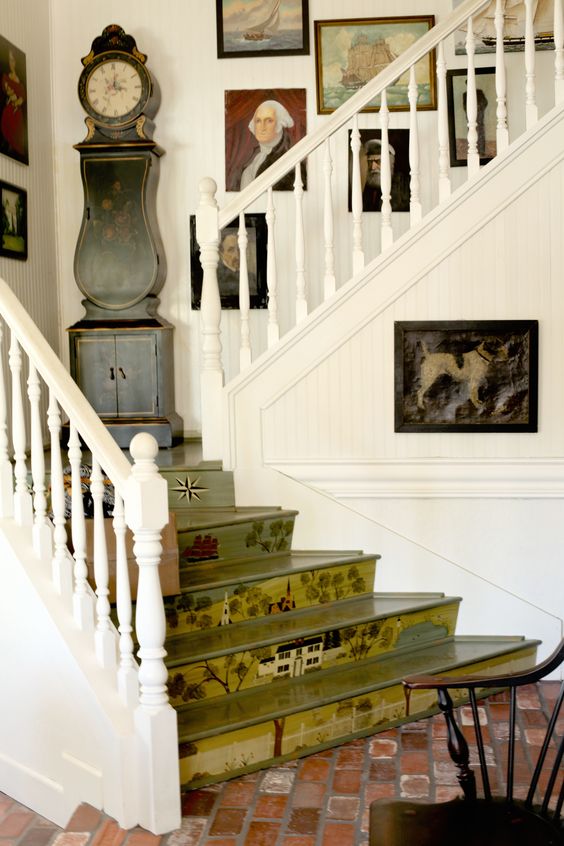 a quirky vintage space in neutrals, with a green staircase with painted steps, a grey grandfather clock and a bold gallery wall over the stairs