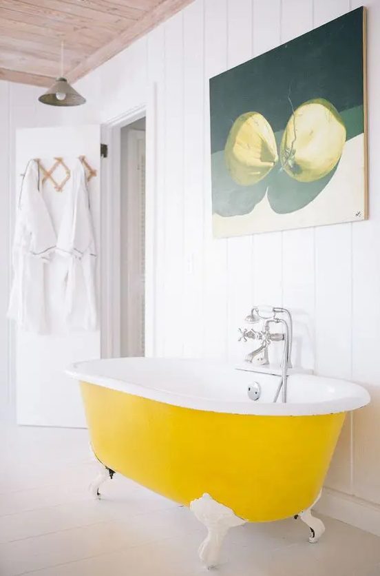 a pure white bathroom with shiplap walls, a bold yellow clawfoot bathtub, a pretty artwork and neutral textiles is cool