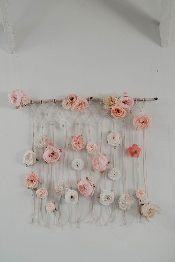 a boho macrame wall hanging with pastel faux blooms is a beautiful decoration for a free-spirited space