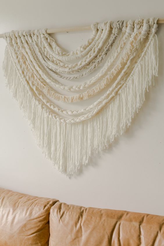 a neutral large scale braided wall hanging with long fringe is a great idea for a boho touch in the space